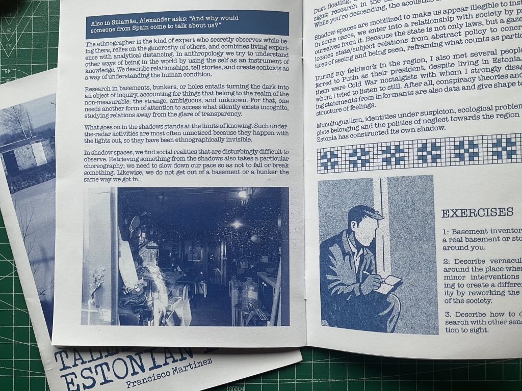 Open zine on a cutting mat showing a blue-toned spread with text blocks, a basement photo, and an illustrated figure next to an “EXERCISES” section.